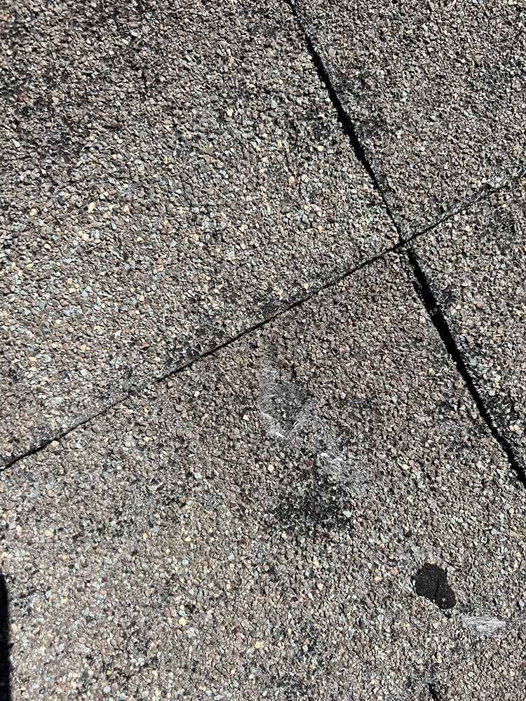 Close view of impact damage to an asphalt shingle